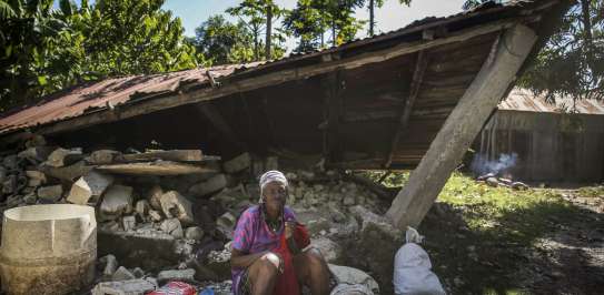 Woman sits in front of a destroyed house after the earthquake in Camp-Perrin, Les Cayes, Haiti