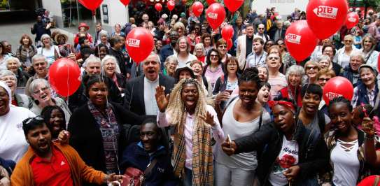 Large group of smiling supporters holding red Christian Aid balloons