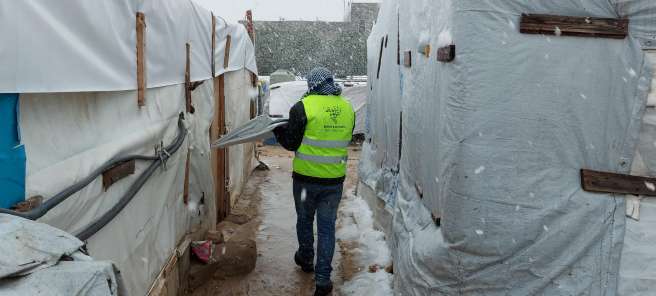 A volunteer in hi-vis Basmeh and Zeitooneh vest repairing the shelters.