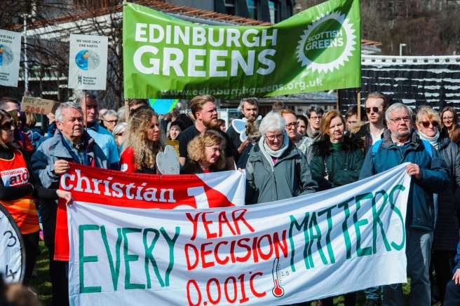 global climate strike activists holding a banner reading "EVERY YEAR, DECISION, 0.001c MATTERS"