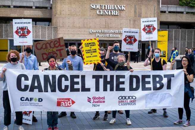 Protesters holding a long banner with the words "Cancel the debt" printed on to it