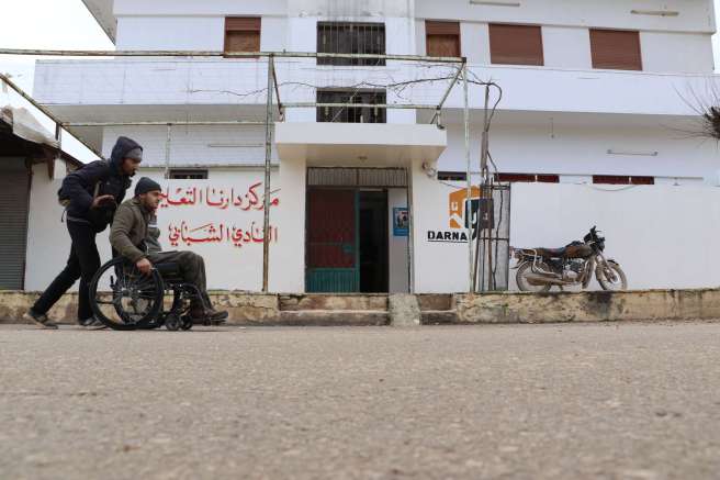 Omar's friend pushes his wheelchair to help him go to school