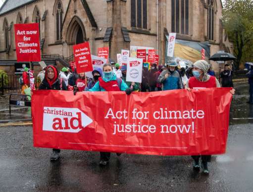 Advocates against climate change stand behind their banner during their march in Glasgow.