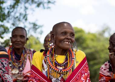 Local woman sits in traditional dress in her Maasai village, Narok County Kenya