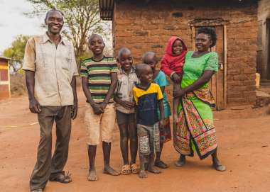 Faith Muvili poses with her family (husband and 5 children) in front of their house.