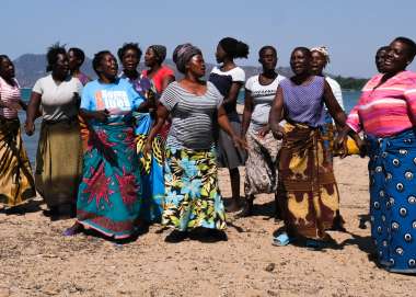 Women participating in the breaking the barriers project dance on the shore