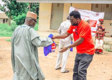 3695 - Christian Aid staff handing over a prepacked bag of non-food items to an excited recipient