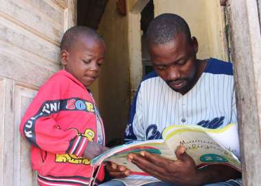 Rafael Cassinda with his youngest son Manuel in the doorway of their home in Angola