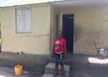 Vilia Marie Odinot, 49, stands in front of her disaster resistant home in Torbeck, South Haiti.